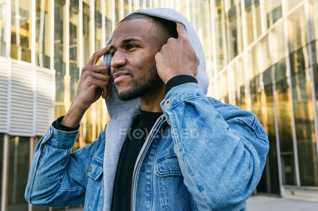 Adult bearded African American male in casual apparel looking forward in town in daylight — Photo de stock