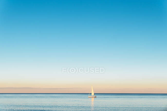 Vista panorámica del velero en el océano ondulado con horizonte bajo el cielo brillante a la luz del día - foto de stock