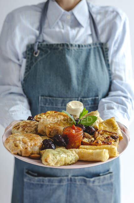 Anonyme Köchin zeigt Teller voller traditioneller arabischer Speisen mit Soßen und frischen Minzblättern während der Ramadan-Feiertage — Stockfoto