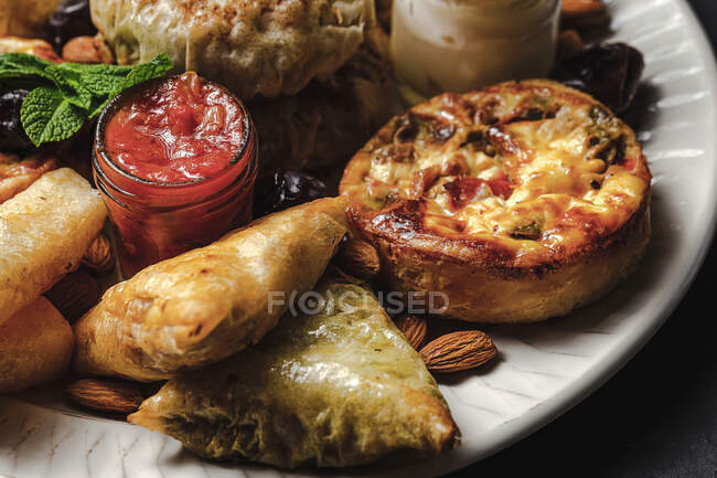 Alto angolo di assortimento gustoso cibo arabo con salsa e foglie di menta fresca vicino alle mandorle durante le vacanze Ramadan — Foto stock