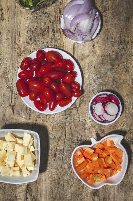 Верхний вид композиции различных свежих овощей, включая редьку помидоры черри лук на деревянный стол — стоковое фото