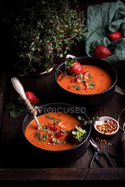 Зверху композиція зі смачними домашніми помідорами і полуницею суп Gazpacho подається в мисках на сільському дерев'яному столі — стокове фото