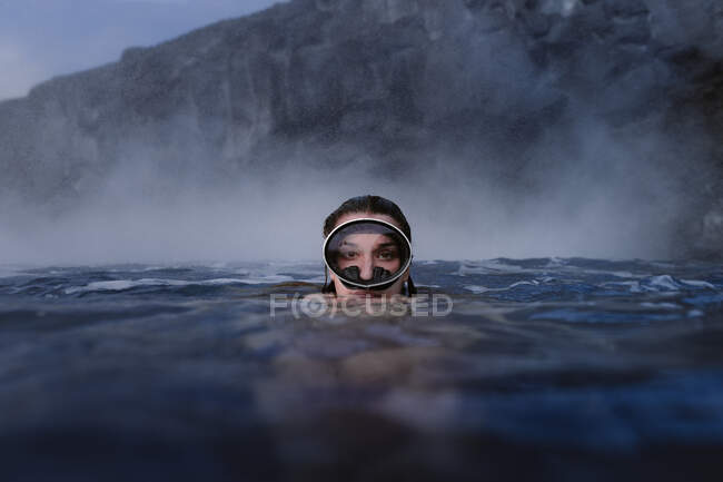 Жінка з окулярами занурюється в море, дивлячись на камеру — стокове фото