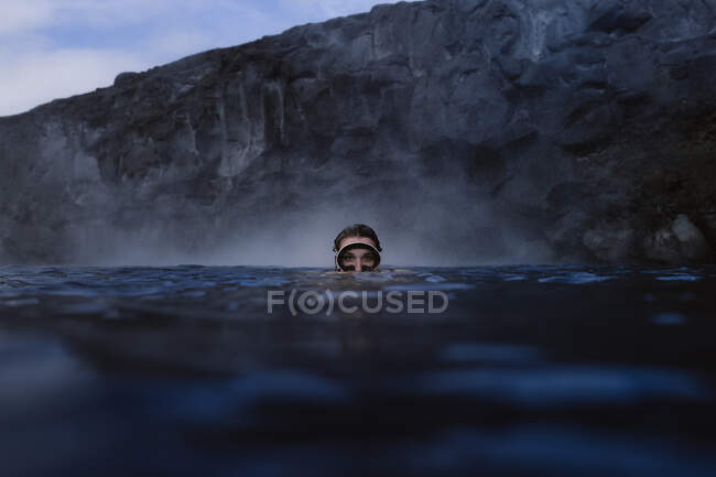 Woman with goggles diving into the sea looking at camera — Stock Photo
