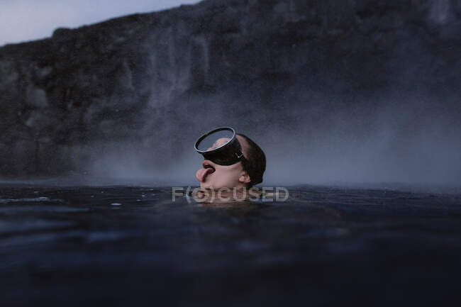 Mujer con gafas sumergiéndose en el mar sobresaliendo de la lengua - foto de stock
