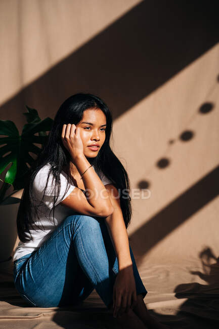 Attraktive junge hispanische Frau trägt weißes Tuch, das das Gesicht berührt, während sie im Sonnenschatten wegschaut — Stockfoto