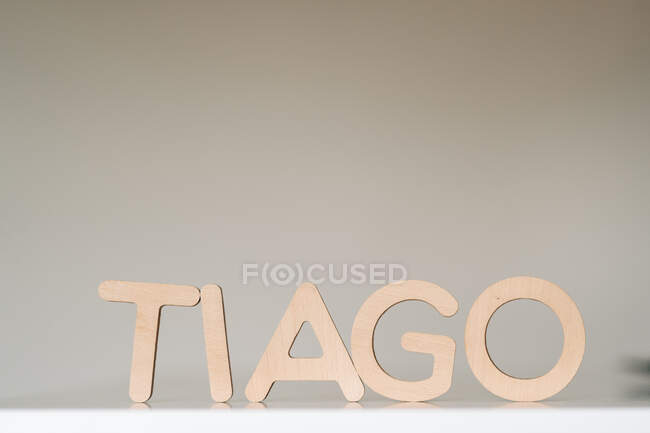 Tiago word made with wooden alphabet letters placed on white table in light room — Photo de stock