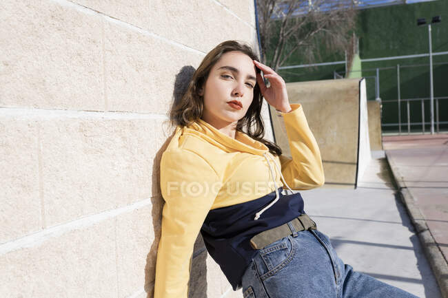 Зовнішній вигляд дівчини - підлітка з гримом у модному одязі торкається чола, дивлячись на камеру в місті. — стокове фото