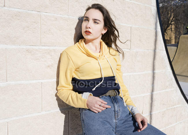 Side view of female teen with makeup in trendy wear touching forehead while looking away in city — Stock Photo