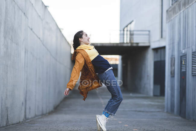 Side view of content female teenager in casual clothes having fun on city road while looking forward — Fotografia de Stock
