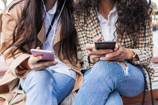 Las mujeres de las cosechas escuchando música y navegar por Internet en el teléfono móvil - foto de stock