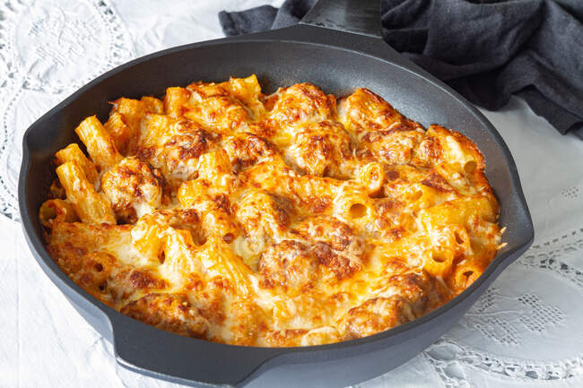Appetizing gratin macaroni with meatballs and tomato sauce with mozzarella cheese prepared and served in skillet on table — Photo de stock