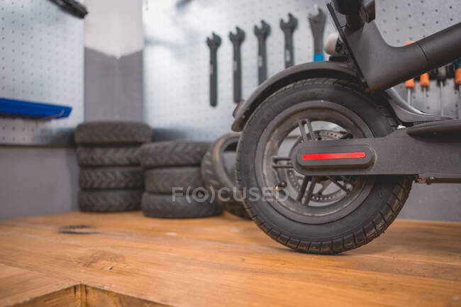 Incomplete electric scooter placed near wall with various repair tools and instruments in modern workshop — Stock Photo