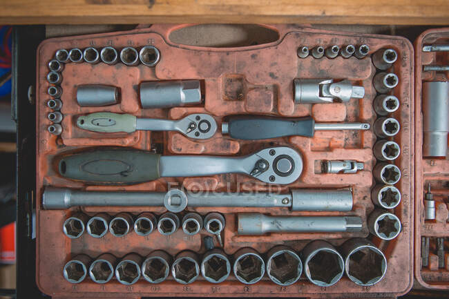 From above of old box with screwdriver and various nozzles and wrenches for auto maintenance and repair service on wooden table — Fotografia de Stock