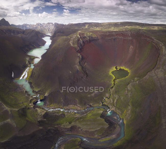 Increíble vista del bucle del río azul curvado que fluye en terreno montañoso áspero cubierto con abundante vegetación exuberante en Islandia - foto de stock