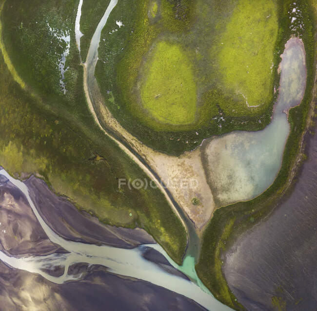 Сверху удивительный вид реки, протекающей по местности, покрытой пышной растительностью в Исландии — стоковое фото
