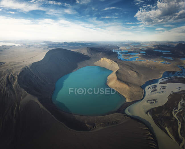 Wonderful scenery of crystal clear lake on vulcan crater surrounded by rough mountain range covered with dry vegetation on clear day — Stock Photo