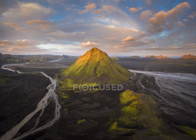 Establecimiento de tiro del vasto valle cubierto de hierba y muchos ríos estrechos con curvas cerca de colinas desoladas ásperas contra el cielo azul en Islandia - foto de stock
