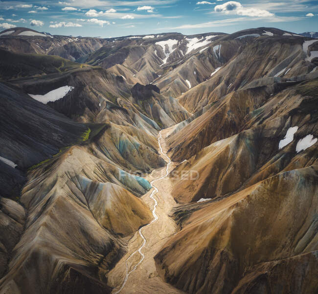 Luftaufnahme eines malerischen, weitläufigen Tals mit einem schmalen, geschwungenen Fluss, der zwischen rauen Bergen unter wolkenverhangenem Himmel fließt — Stockfoto