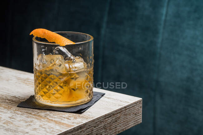 Tasse en verre Tiki avec boisson à l'ancienne placée sur la table sur fond flou — Photo de stock