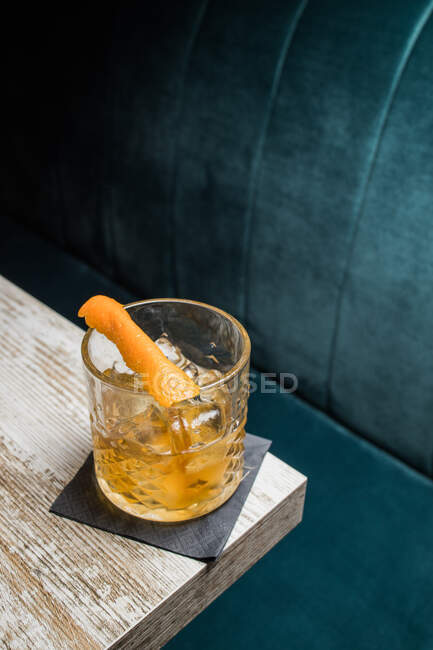Скляний кухоль Тікі зі старомодним напоєм, розміщеним на столі на розмитому фоні — стокове фото