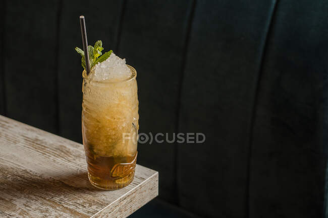 De cima de copo tiki com bebida alcoólica fria com palha servida com gelo e decorada com erva fresca colocada sobre fundo turvo — Fotografia de Stock