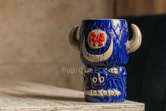 Bull shaped tiki mug of alcohol drink with froth placed against wooden table on blurred background — Stock Photo