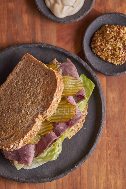 Primer plano de un delicioso sándwich de pastrami, lechuga, jamón y pepinillo - foto de stock