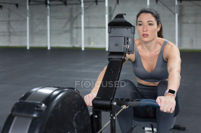 Deportiva haciendo ejercicios en máquina de remo - foto de stock