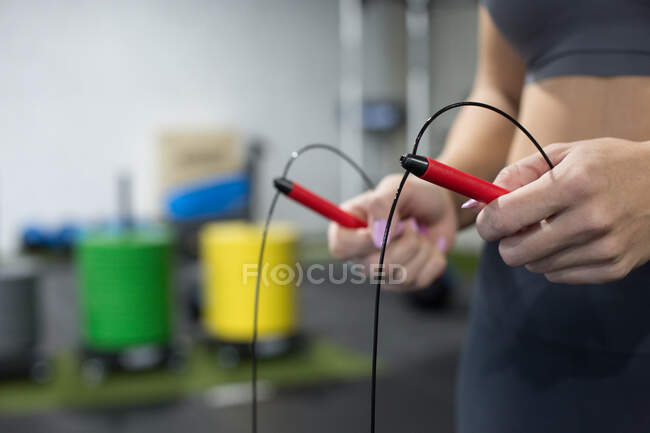Невпізнавана струнка жінка в спортивному манері робить вправи з стрибкоподібною мотузкою під час функціонального тренування в спортивному клубі. — стокове фото