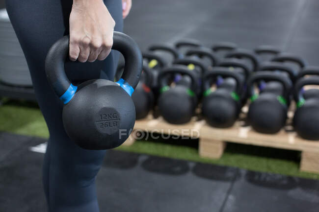 Crop anonymous athletic female in sportswear doing exercises with heavy kettlebell during functional workout in gym — Stock Photo