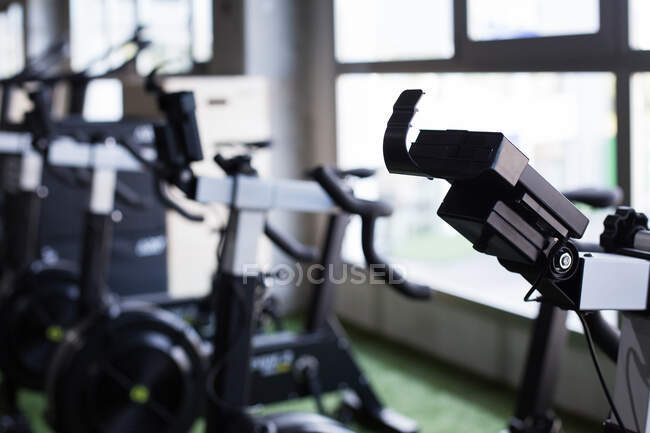 Bicicletas fijas para un entrenamiento funcional intenso colocadas en fila en un moderno club deportivo equipado - foto de stock