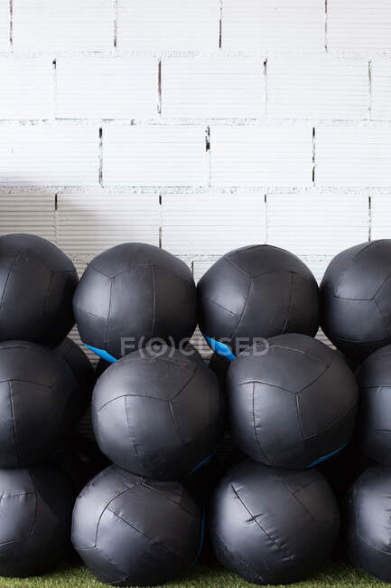 Conjunto de bolas de medicina preta para treinamento funcional empilhadas em fileiras perto da parede no clube de esportes moderno — Fotografia de Stock