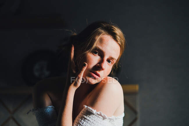 Retrato de jovem mulher sem emoções com ombros nus no balcão da cozinha e olhando para a câmera com calma — Fotografia de Stock