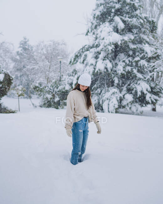 Joven hembra feliz de pie en el parque de nieve de invierno con árboles blancos en Madrid con los ojos cerrados - foto de stock