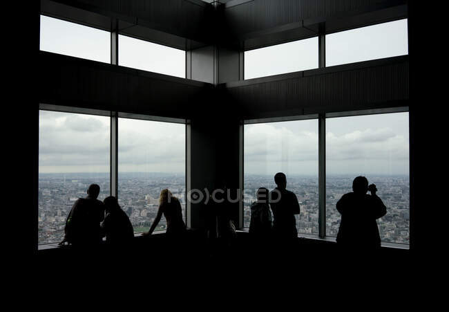 Silhouetten unkenntlich gemachter Touristen mit Blick auf die Skyline von einem hohen Wolkenkratzer in Tokio — Stockfoto