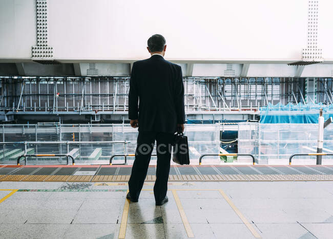 Back view of unrecognizable businessman passenger with backpack standing on platform of subway station in Tokyo — Stock Photo