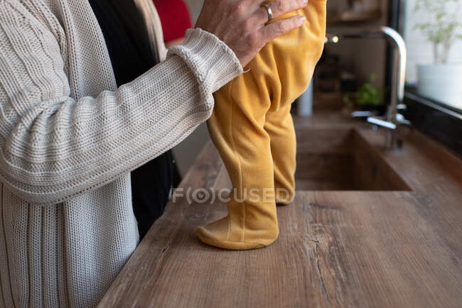 Vue latérale de la récolte père aimant méconnaissable avec tout-petit debout sur le comptoir dans la cuisine — Photo de stock