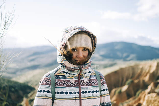 Молодой турист в теплой одежде смотрит в камеру на монтировках во время поездки в Испанию — стоковое фото