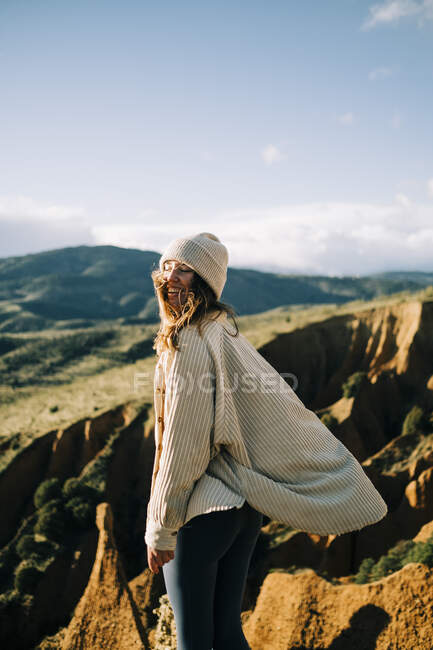 Vista lateral de la alegre turista de pie con los ojos cerrados en el desfiladero contemplando verdes montañas en España - foto de stock
