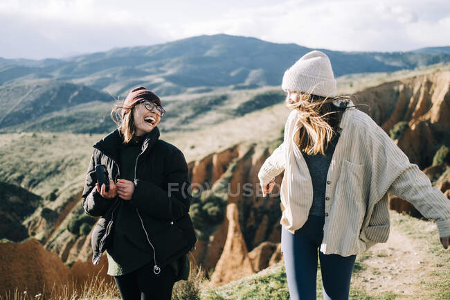 Giovani viaggiatori femminili felici con fotocamera fotografica divertirsi contro il montaggio nella giornata di sole in retroilluminazione — Foto stock