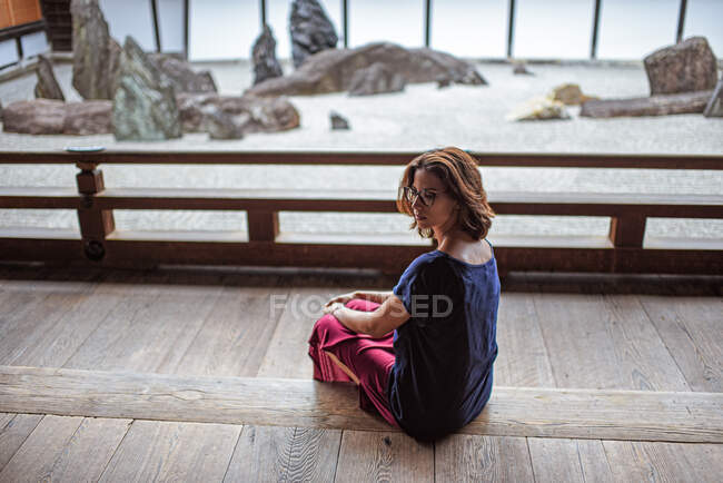 Contemplative young attractive caucasian woman enjoys calm in a traditional zen stone garden at a Buddhist temple, Kyoto, Japan — Stock Photo