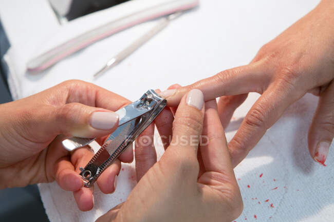 From above of crop anonymous beauty master trimming nail of woman with cutter during manicure procedure — Stock Photo