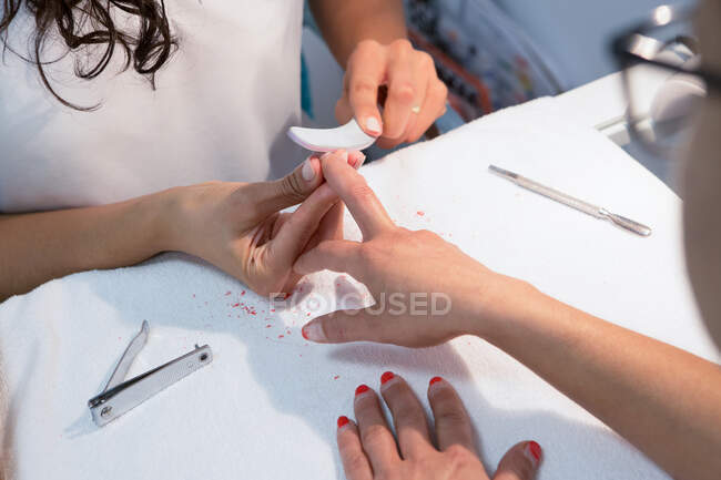 From above of crop anonymous beauty master trimming nail of woman with cutter during manicure procedure — Stock Photo