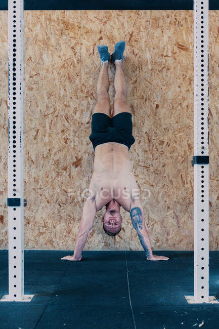 Starker männlicher Athlet mit nacktem Oberkörper balanciert beim funktionellen Training auf dem Handstand — Stockfoto
