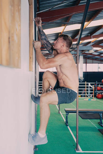 Seitenansicht des muskulösen männlichen Athleten beim Klettern des Wirbelbretts beim funktionellen Training im Fitnessstudio — Stockfoto