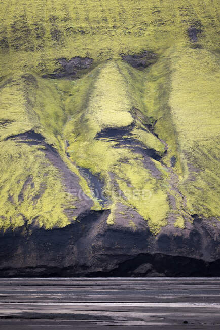 De cima de terreno rochoso coberto com plantas verdes localizadas em terras altas da Islândia — Fotografia de Stock