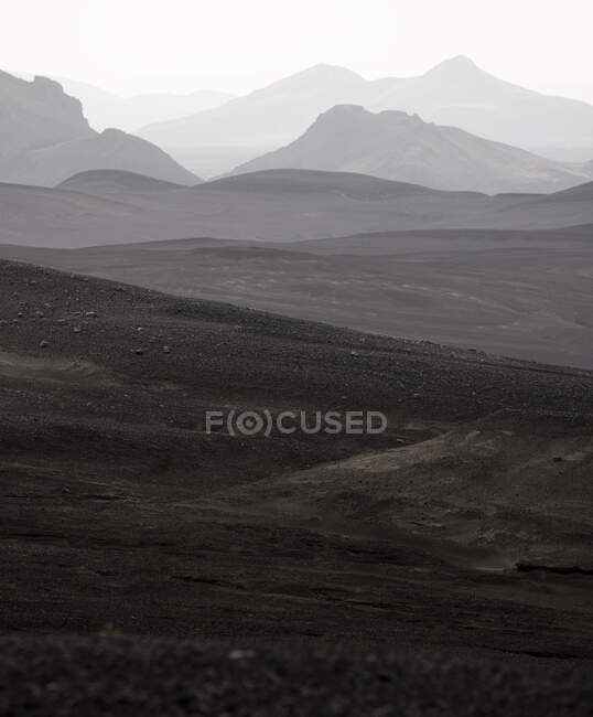 Живописный пейзаж грубого горного хребта с вершинами в густом тумане под мрачным небом в высокогорье — стоковое фото