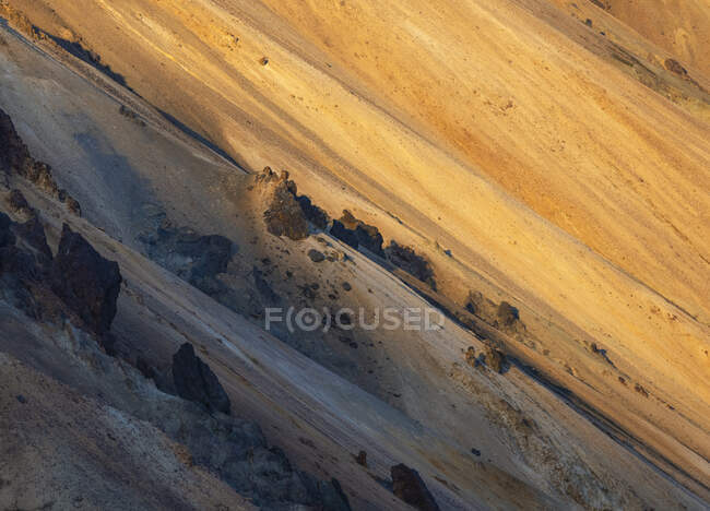 Magnífico paisaje de montañas rocosas con picos iluminados por la luz del sol en terrenos desérticos en Islandia - foto de stock