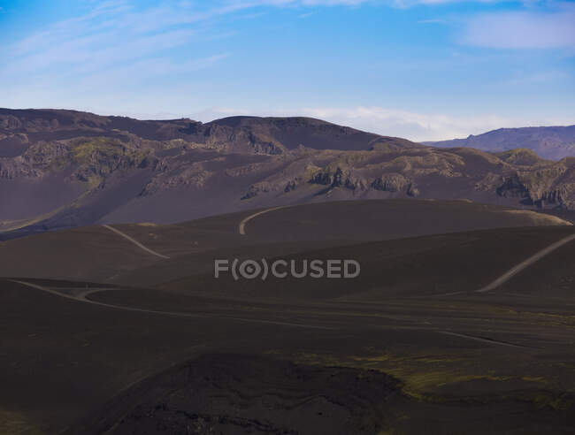 Сценічний вид горбиста дорога оточена нерівною кам'янистою долиною під безхмарним яскравим блакитним небом. — Stock Photo